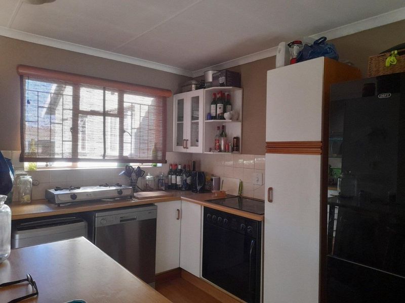 A functional kitchen featuring built-in cabinetry, laminate countertops, a gas hob, and a built-in oven with tiled backsplash and security-barred window.