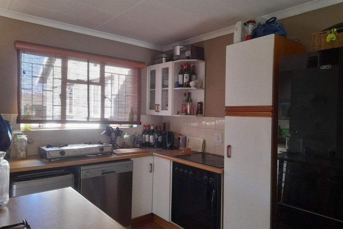 A functional kitchen featuring built-in cabinetry, laminate countertops, a gas hob, and a built-in oven with tiled backsplash and security-barred window.