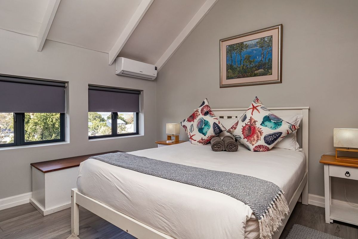 A well-maintained bedroom featuring a vaulted ceiling with exposed rafters, split-system air conditioning, and built-in window seating with views.