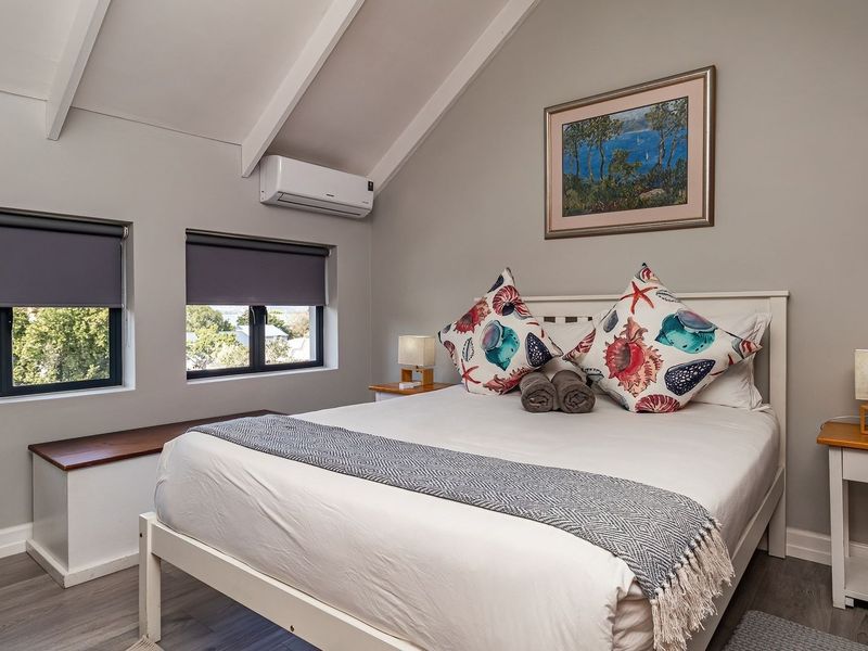 A well-maintained bedroom featuring a vaulted ceiling with exposed rafters, split-system air conditioning, and built-in window seating with views.