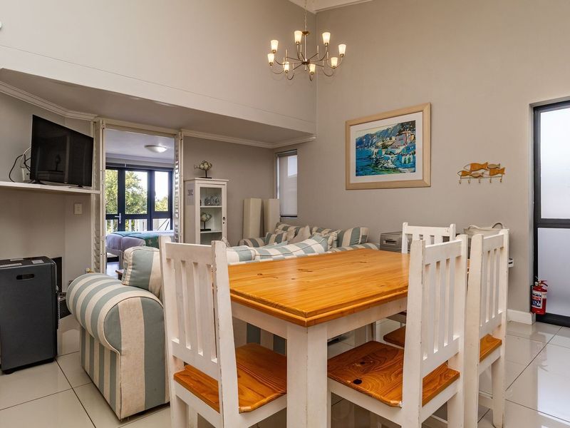 Open-plan living and dining area featuring tiled flooring, a staircase, and access to an adjoining room through a sliding door.