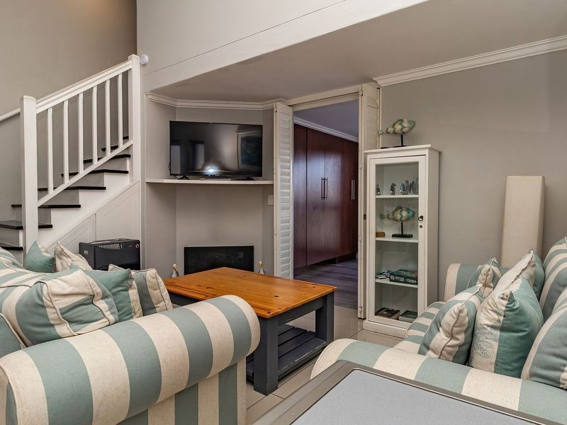 A cozy living room featuring a staircase, a built-in fireplace, and elegant crown molding, providing a comfortable and well-maintained living space.