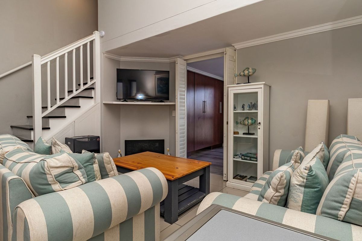 A cozy living room featuring a staircase, a built-in fireplace, and elegant crown molding, providing a comfortable and well-maintained living space.
