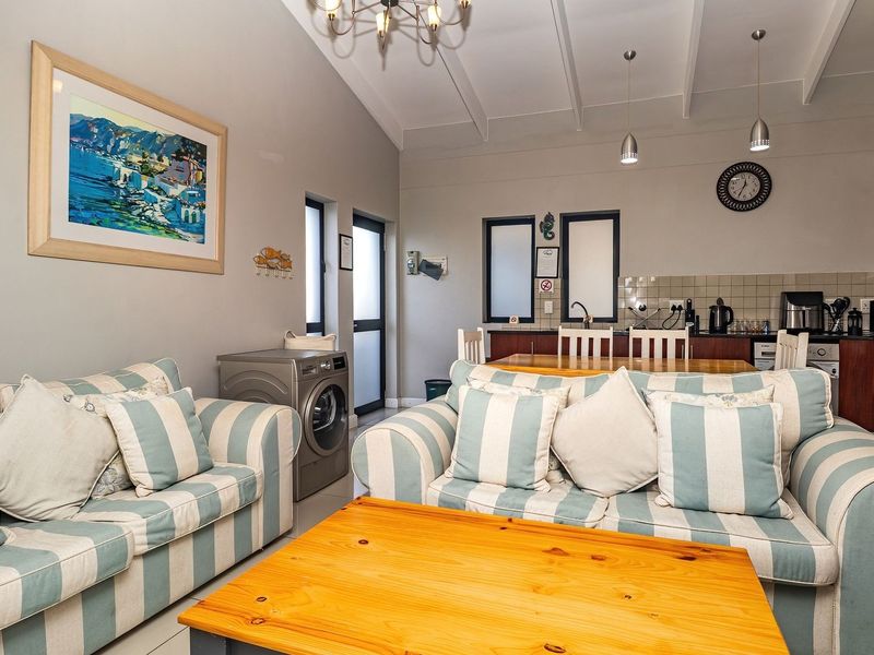 Open-plan living and kitchen area featuring vaulted ceilings with exposed beams, tiled flooring, and a functional kitchen with built-in cabinetry and appliances.