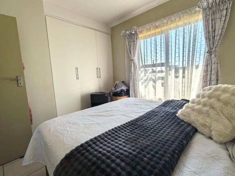 A bedroom featuring built-in cupboards and tiled flooring, offering a functional space with natural light.