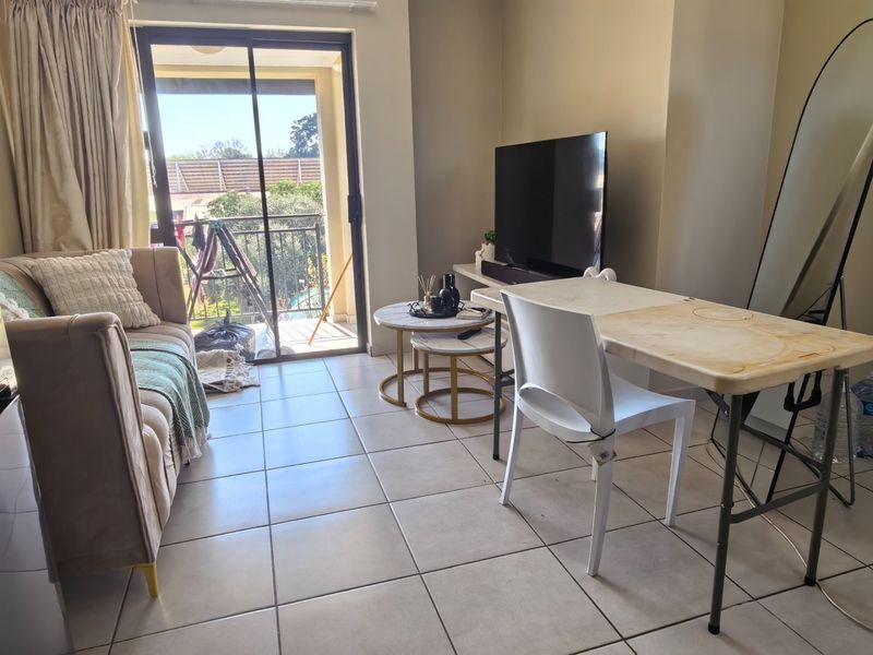 A living room area featuring ceramic floor tiles and a sliding glass door providing direct access to an outdoor balcony.