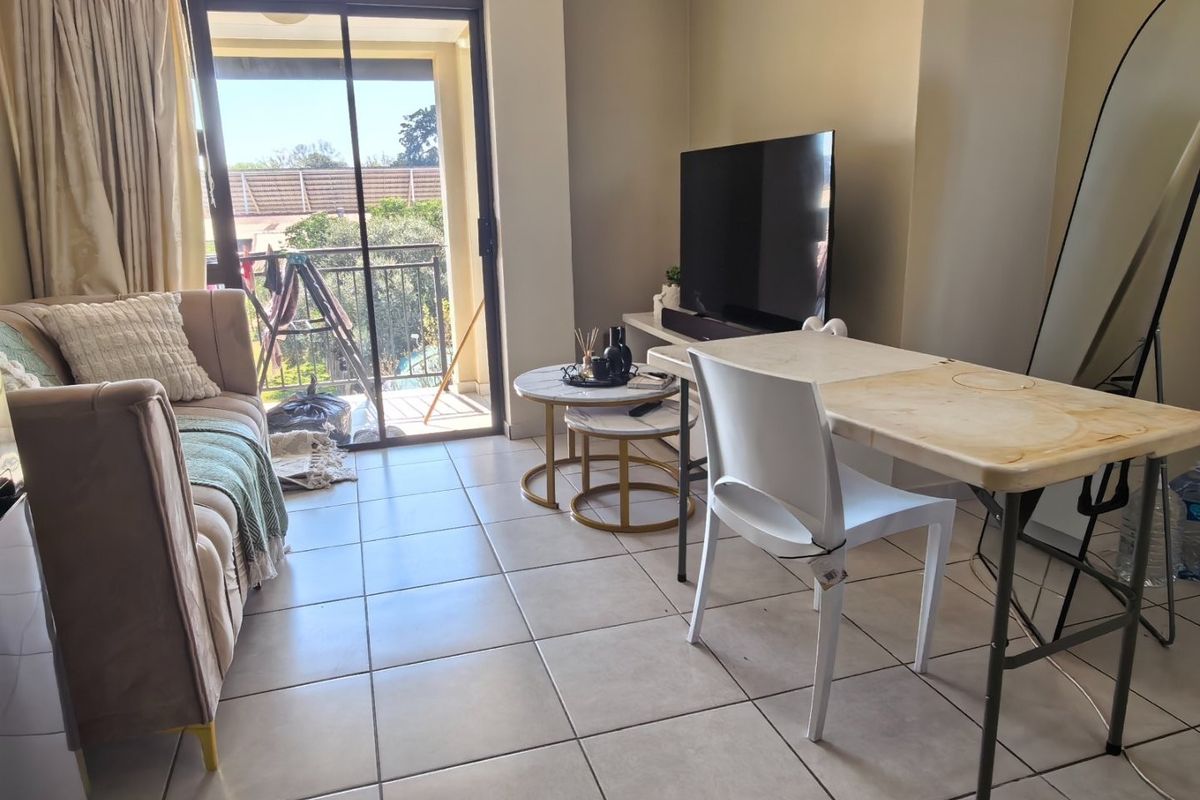 A living room area featuring ceramic floor tiles and a sliding glass door providing direct access to an outdoor balcony.