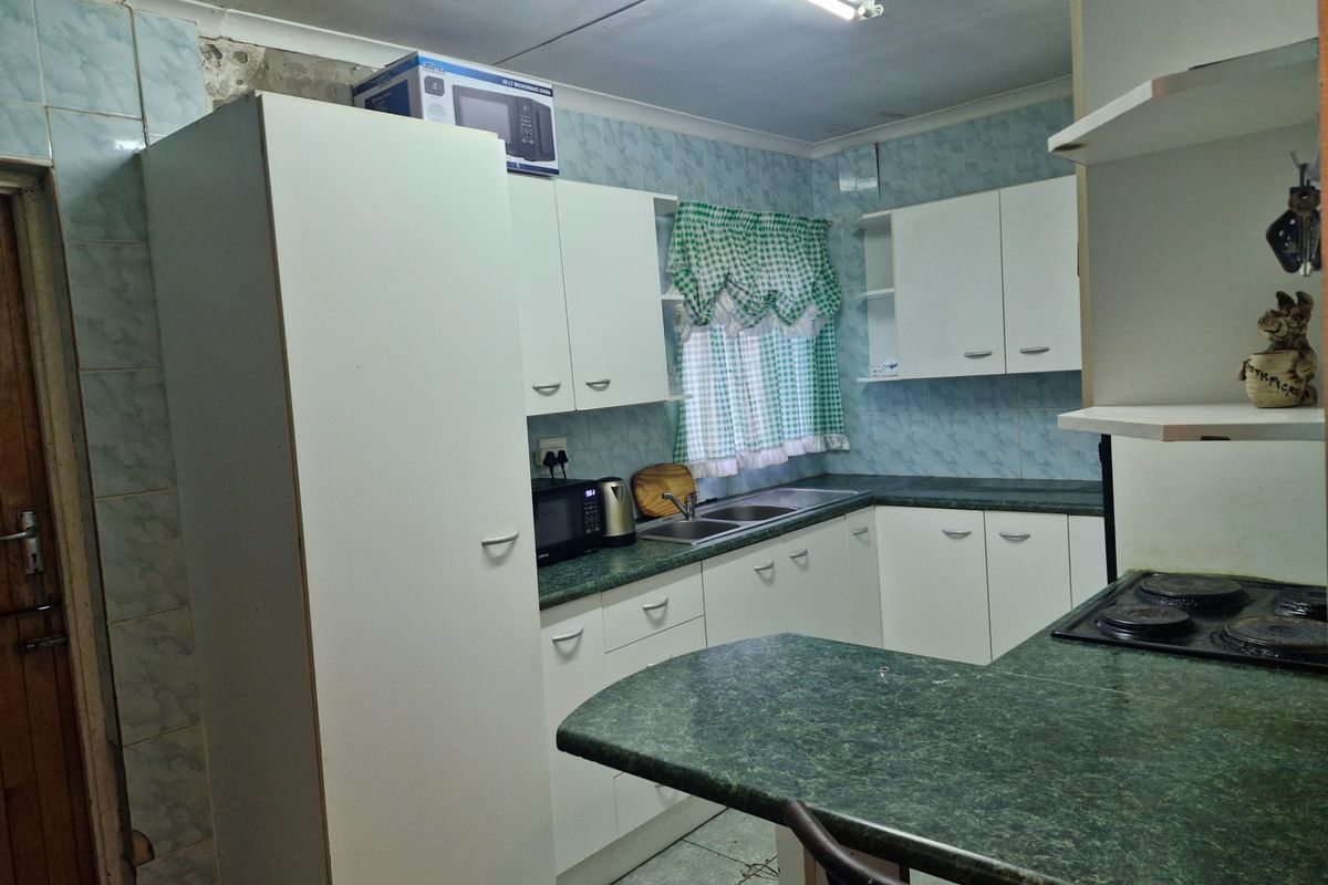 A functional kitchen featuring laminate countertops, built-in cabinetry, and a double bowl sink, offering potential for modernization and cosmetic updates.