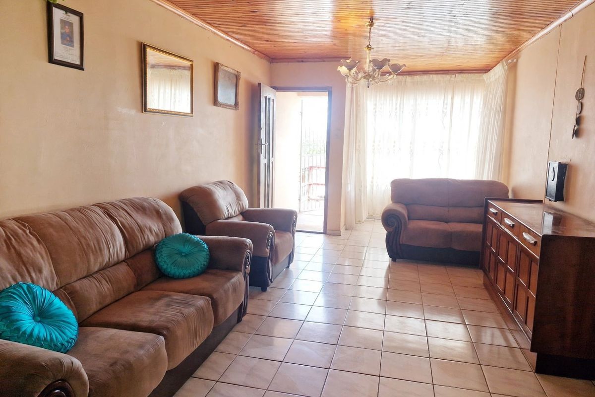 A living room featuring a timber tongue and groove ceiling, ceramic tiled flooring, and a chandelier, with access to an outdoor area.