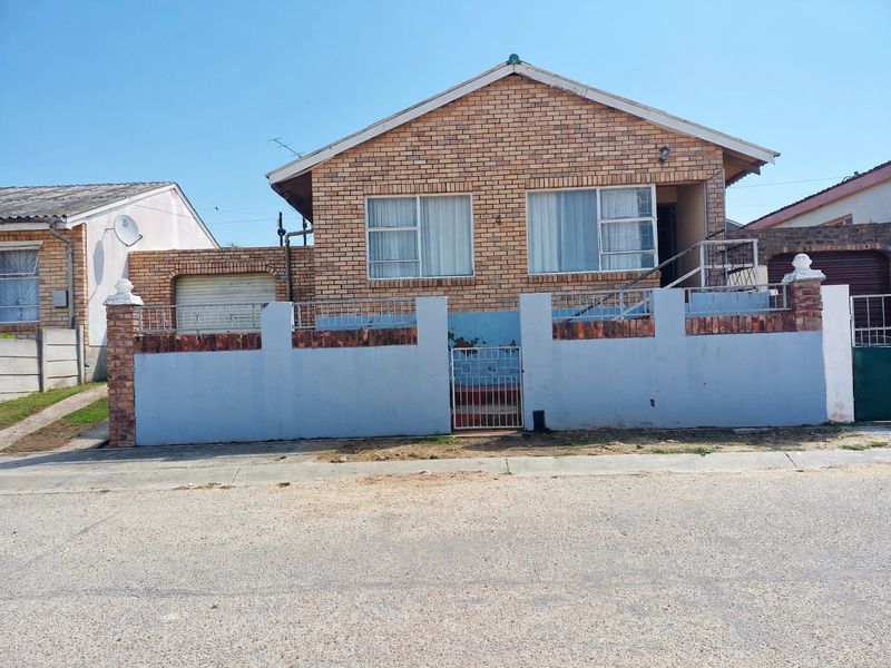 Front view of a single-story face brick house featuring a perimeter wall, metal gate, and integrated garage.