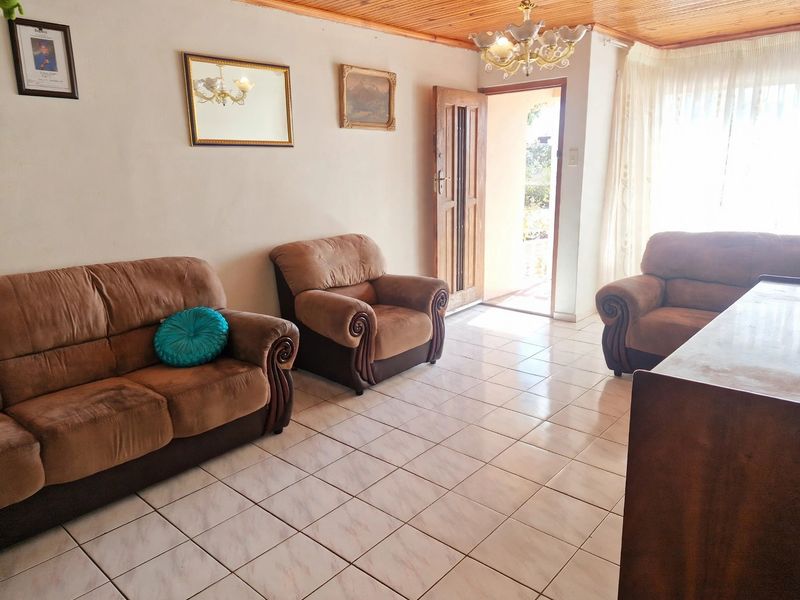 A living room featuring tiled flooring, a timber tongue and groove ceiling, and direct access to the exterior through a timber door.