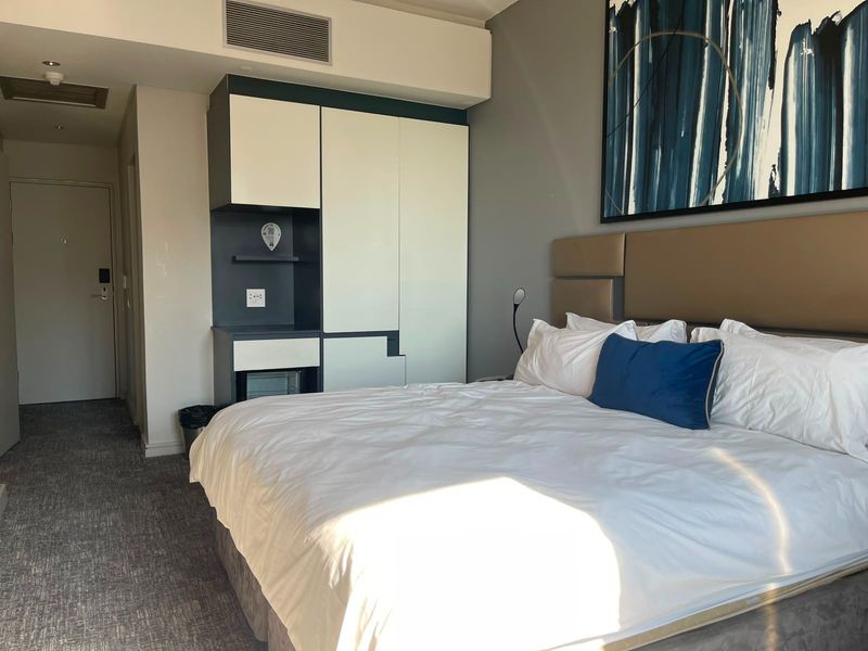 A well-maintained bedroom featuring built-in cabinetry, integrated ducted air conditioning, and a modern upholstered headboard with neutral wall finishes.