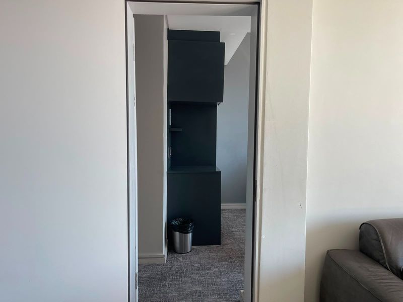 A view through a doorway into a hallway featuring built-in dark cabinetry and neutral carpeting.