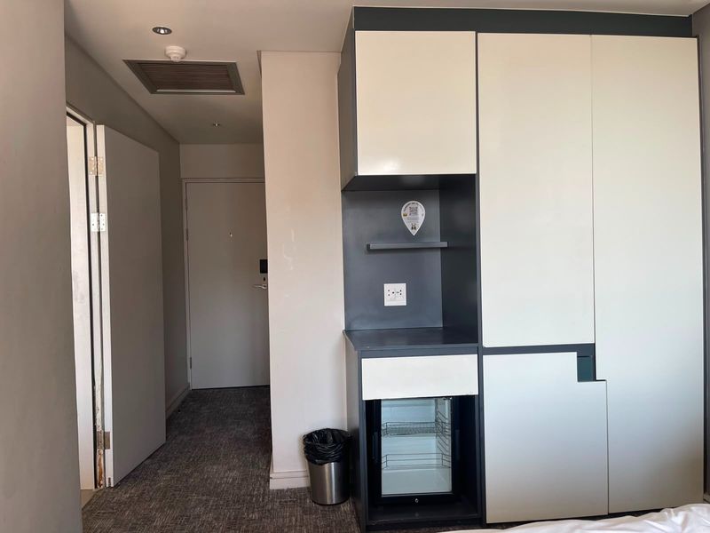 Bedroom interior featuring built-in cabinetry with an integrated mini-fridge, recessed lighting, and carpeted flooring.