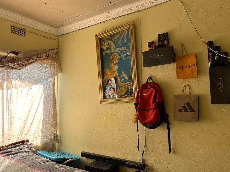 A bedroom featuring yellow walls with visible plaster cracks and traditional ceiling cornicing, requiring cosmetic updates to improve the overall finish.