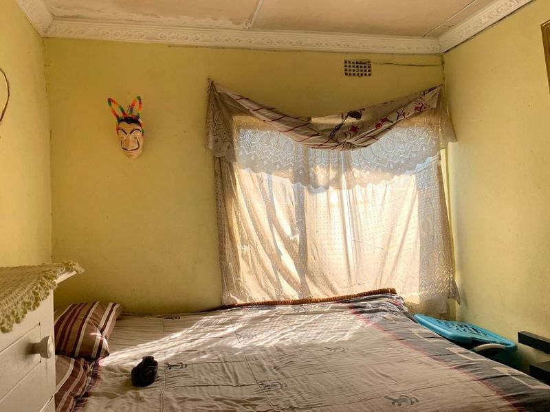 A bedroom featuring decorative ceiling cornicing and a wall-mounted ventilation vent, requiring cosmetic updates to the wall and ceiling finishes.