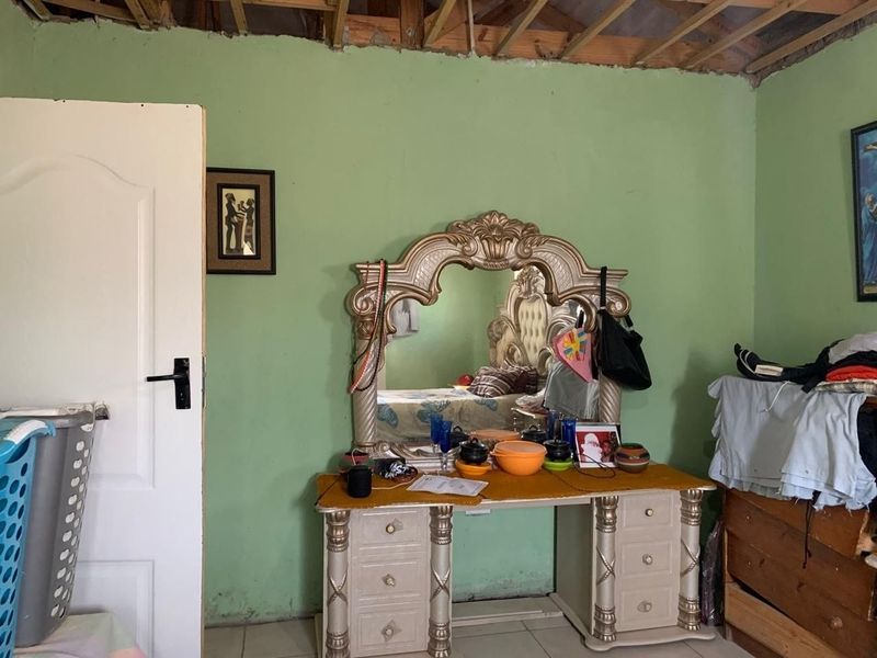 Bedroom featuring green walls and exposed ceiling rafters, requiring ceiling completion and general cosmetic refurbishment.