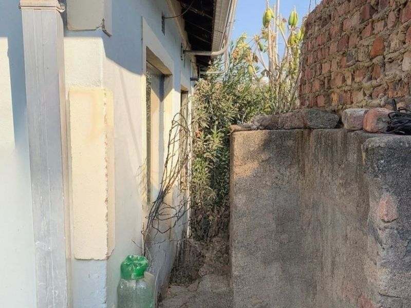A narrow side passage of the property featuring a brick boundary wall with razor wire and an external downpipe.