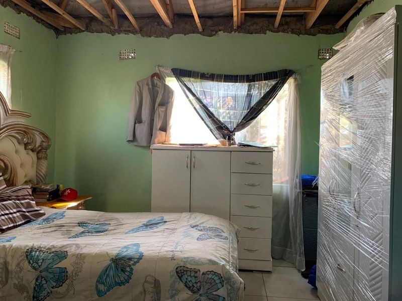 A bedroom featuring tiled flooring and exposed timber ceiling rafters, requiring ceiling completion and general interior finishing to improve the space.