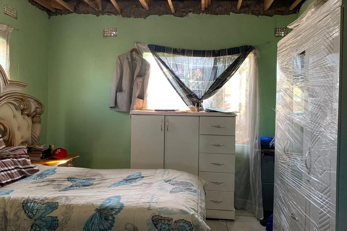 A bedroom featuring tiled flooring and exposed timber ceiling rafters, requiring ceiling completion and general interior finishing to improve the space.