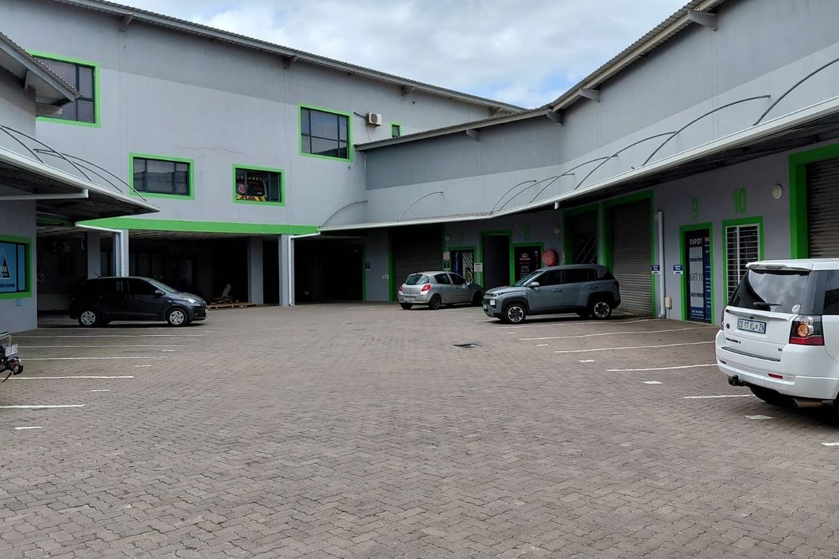 Industrial complex courtyard featuring multiple unit access points with roller shutter doors and a paved parking area.