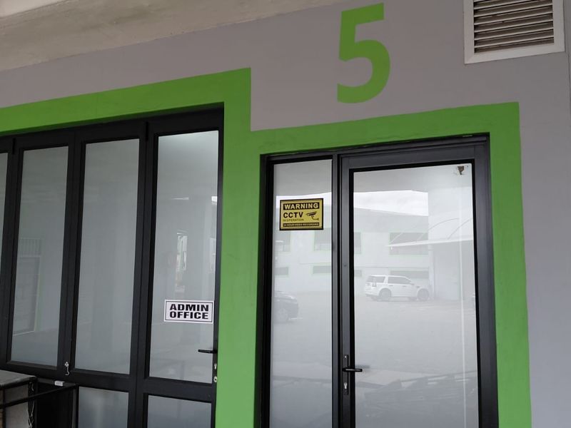 Exterior view of an industrial unit entrance featuring modern aluminium framed glass doors and clear signage for an admin office.