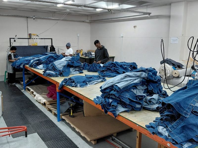 Industrial workspace featuring large work tables, exposed ceiling lighting, and electrical infrastructure, suitable for manufacturing or assembly operations.