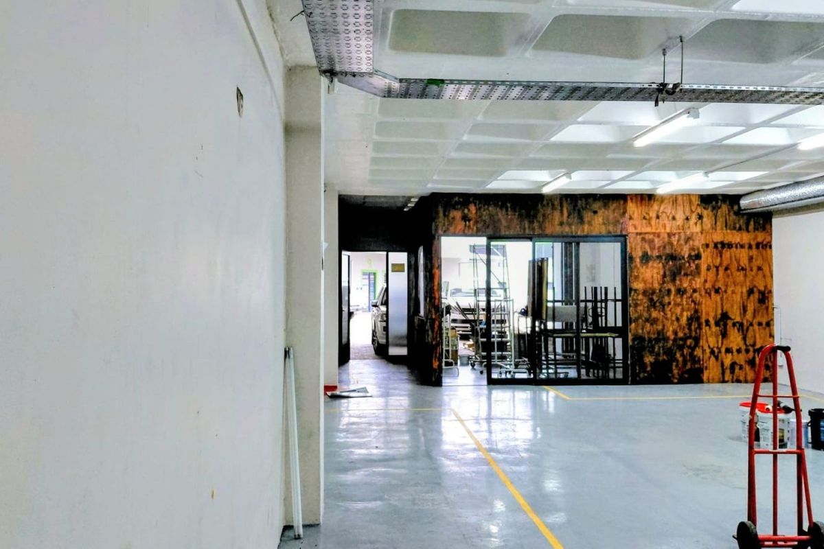 Spacious industrial utility area featuring durable epoxy flooring, exposed waffle slab ceiling, and a glass-partitioned office or storage section.