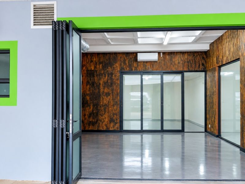 Modern industrial office space featuring polished concrete floors, glass partitions, bi-fold entry doors, and split-system air conditioning.