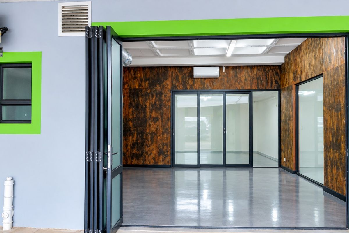 Modern industrial office space featuring polished concrete floors, glass partitions, bi-fold entry doors, and split-system air conditioning.