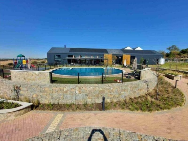 A well-maintained communal pool area featuring a circular swimming pool, stone retaining walls, and paved pathways set against a modern building.