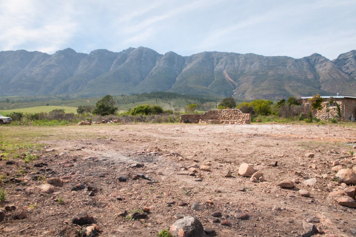 A vacant residential plot featuring a stone wall structure with expansive mountain views in the background.
