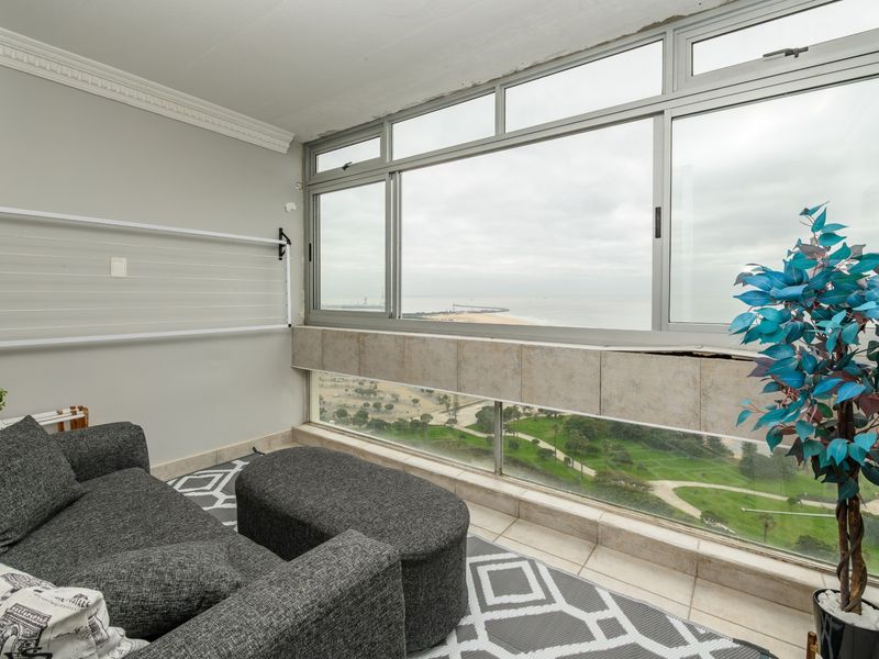 Enclosed balcony featuring large sliding windows with panoramic coastal views, tiled wall accents, and crown molding detail.