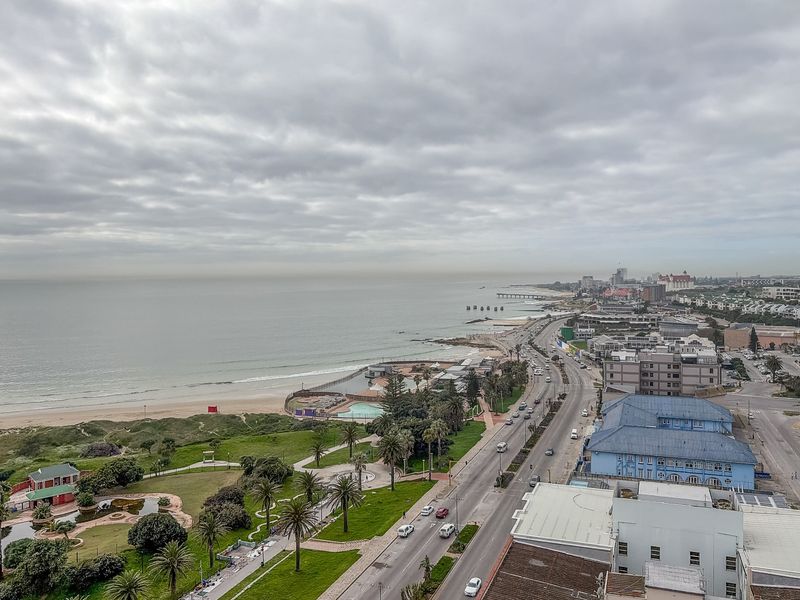 Elevated coastal view overlooking the beach, public park, and surrounding urban infrastructure.