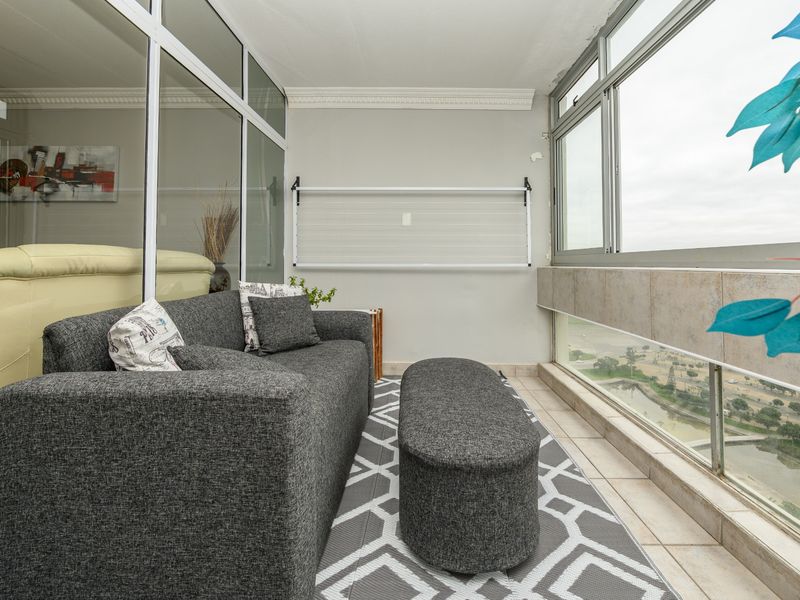 Enclosed balcony featuring tiled flooring, large sliding windows with views, and a wall-mounted drying rack, offering a versatile additional living space.