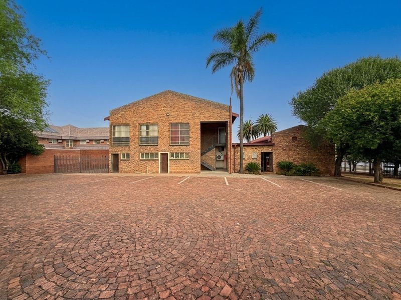 Commercial property exterior featuring a brick facade, paved parking area, and external staircase access.