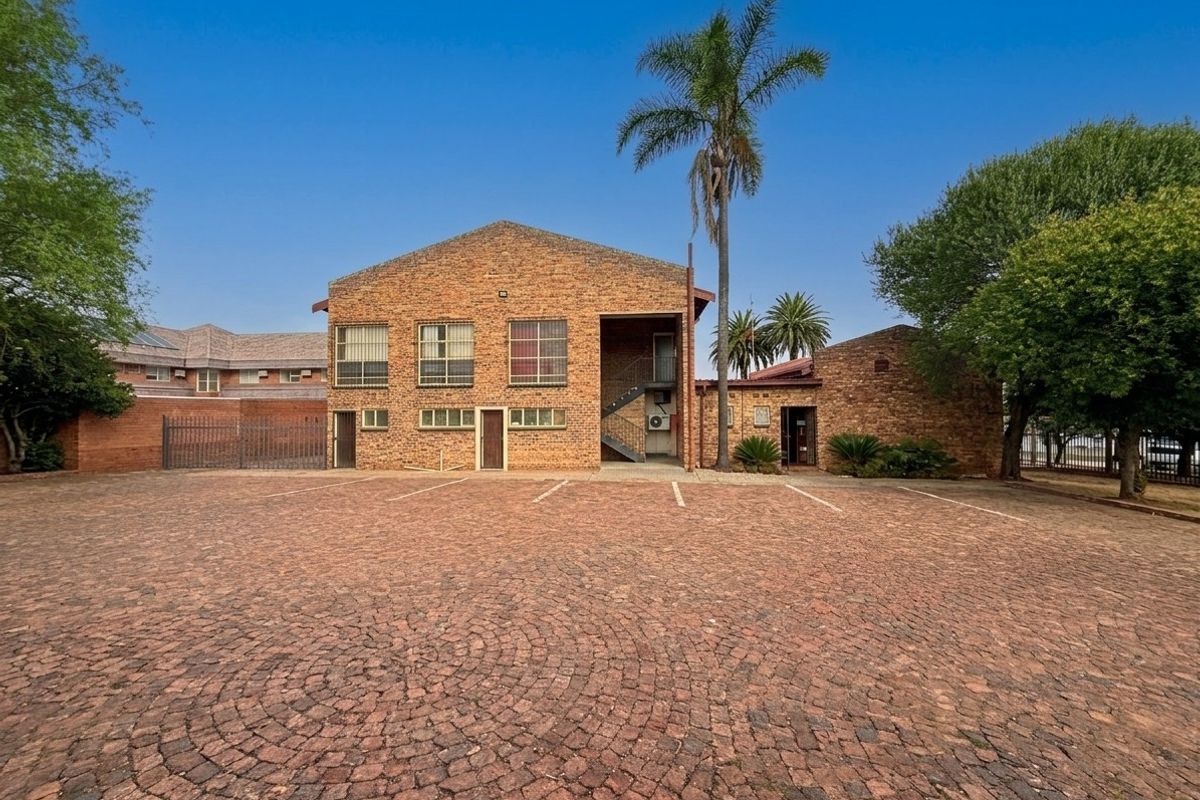 Commercial property exterior featuring a brick facade, paved parking area, and external staircase access.