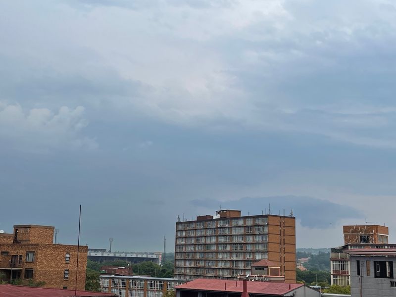 An elevated urban view showcasing surrounding apartment buildings and city infrastructure under a cloudy sky.