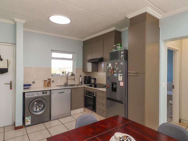 A functional kitchen featuring built-in cabinetry, tiled flooring, a tiled backsplash, and integrated appliances, offering a practical layout for daily use.