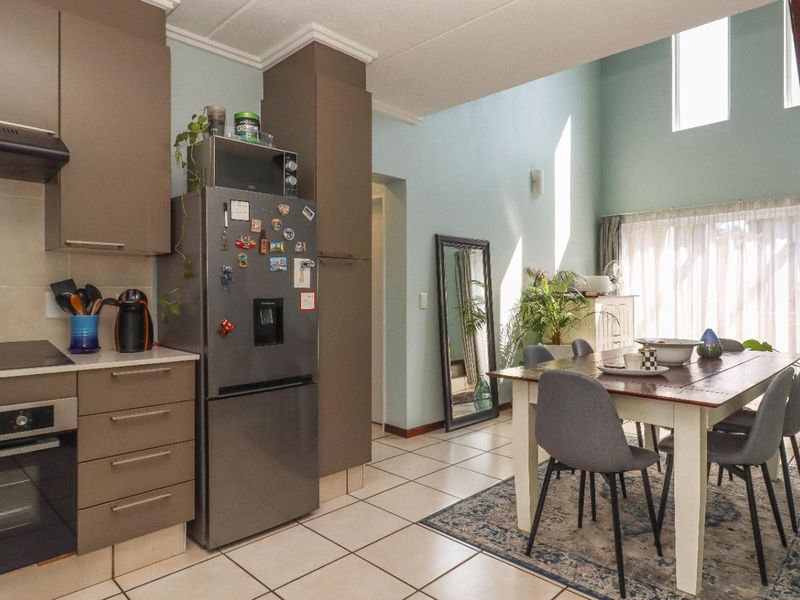 Open-plan kitchen and dining area featuring modern cabinetry, built-in appliances, tiled flooring, and a staircase leading to an upper level.
