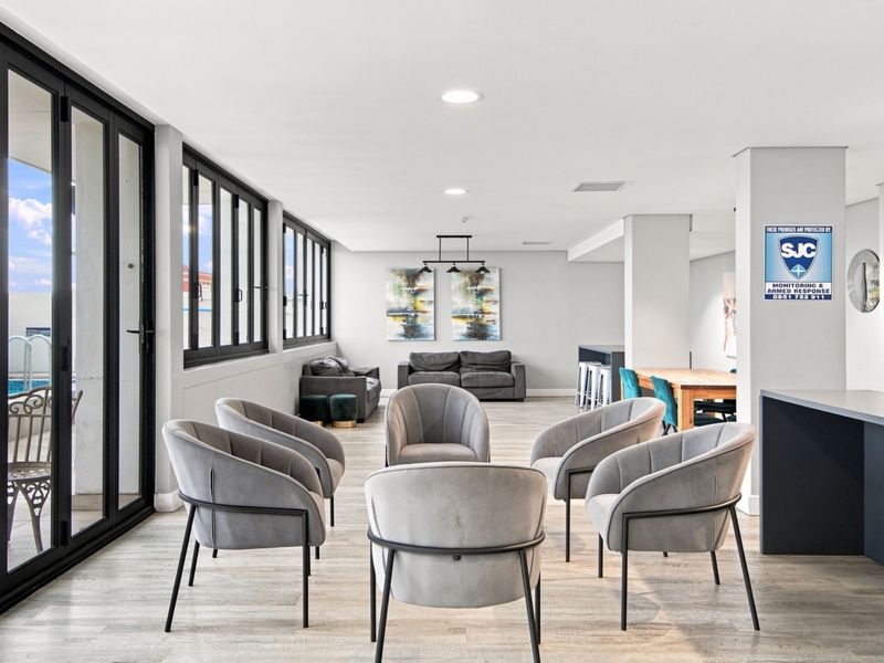 Spacious open-plan living area featuring modern laminate flooring, recessed lighting, and large aluminium sliding doors providing seamless access to the outdoor pool area.