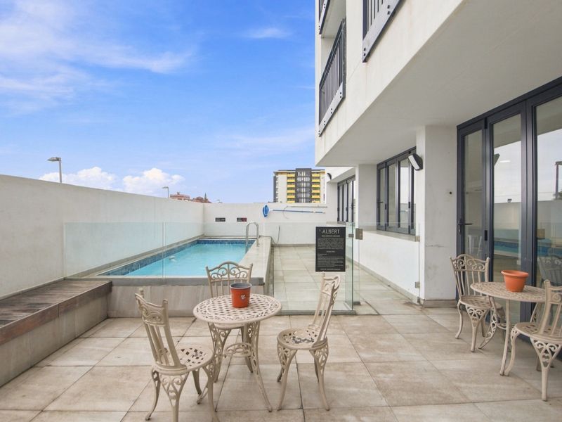 Outdoor terrace area featuring a swimming pool, glass balustrade, and tiled flooring, providing a functional space for relaxation and recreation.