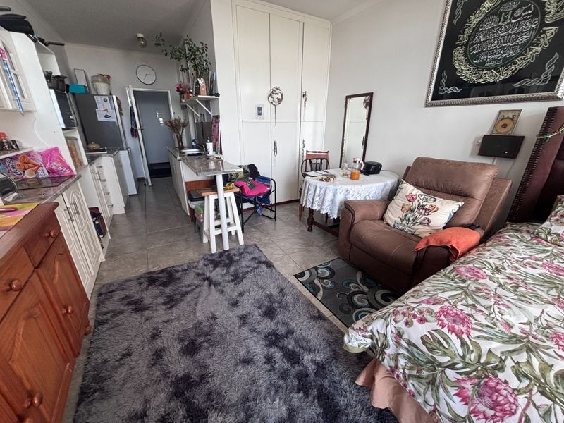 An open-plan living and kitchen area featuring tiled flooring, built-in cabinetry, and integrated storage cupboards in a retirement village unit.