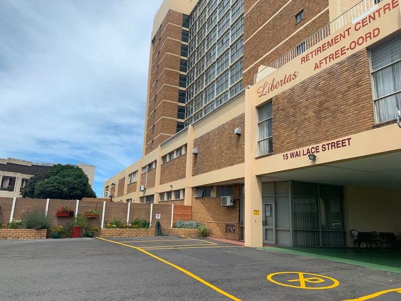 Front exterior view of Libertas Retirement Centre, featuring a brick facade, designated parking bays, and clear building signage.