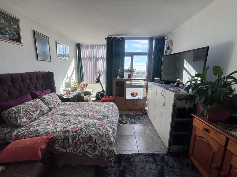 A bedroom featuring tiled flooring and a large window providing natural light and exterior views.