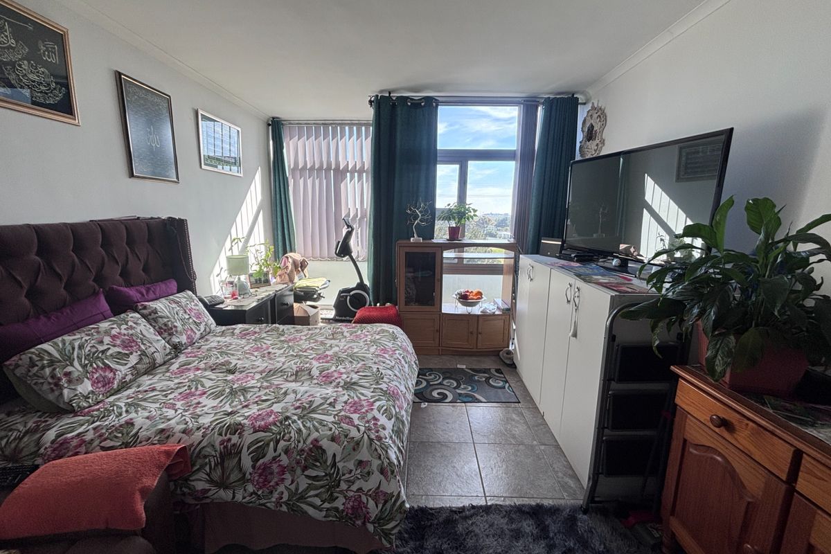 A bedroom featuring tiled flooring and a large window providing natural light and exterior views.