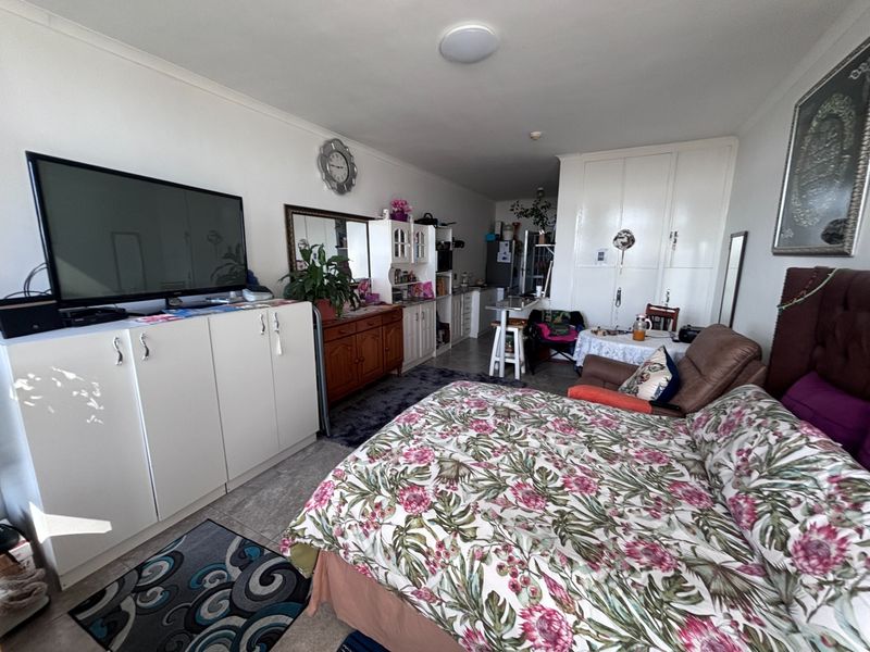 Open-plan living and sleeping area featuring tiled flooring, built-in cabinetry, and ample storage space within a retirement village unit.