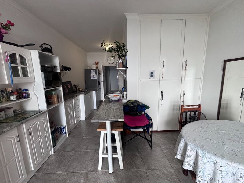 Open-plan kitchen and dining area featuring tiled flooring, ample built-in cabinetry, and a functional breakfast bar for casual dining.