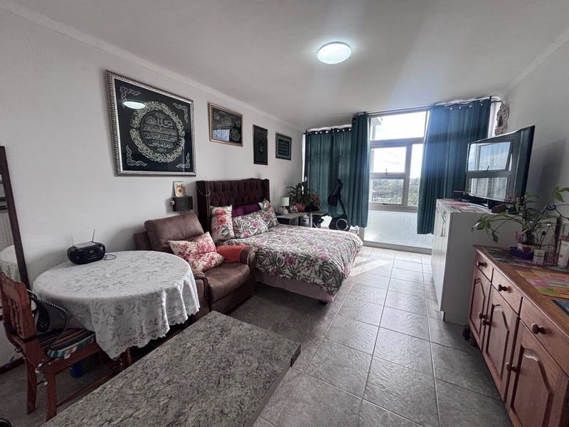 A spacious bedroom featuring tiled flooring and a large window that allows for natural light, providing a comfortable living space.