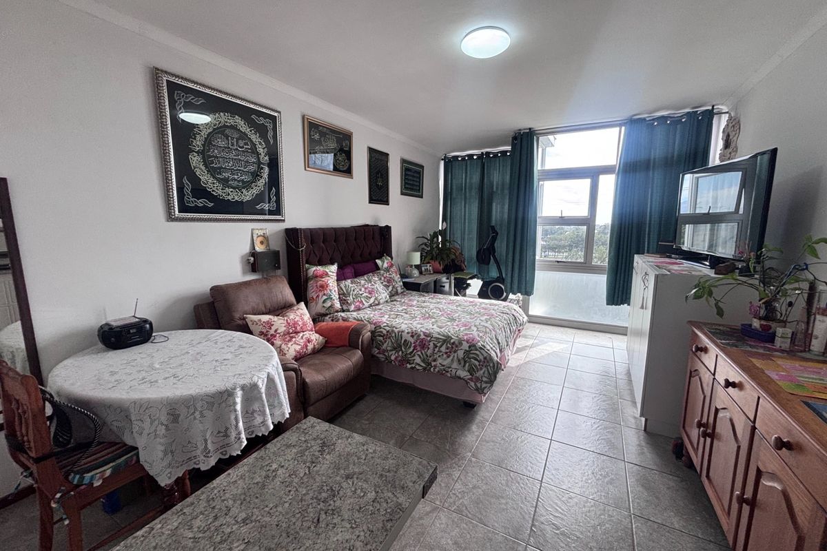 A spacious bedroom featuring tiled flooring and a large window that allows for natural light, providing a comfortable living space.